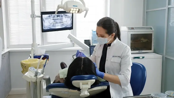 A dentist in a mask working with a patient in a dental treatment room