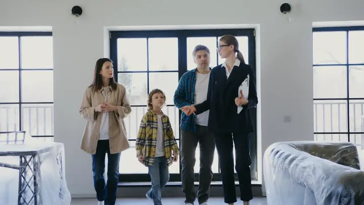 A real estate agent walking a family through an empty, bright home