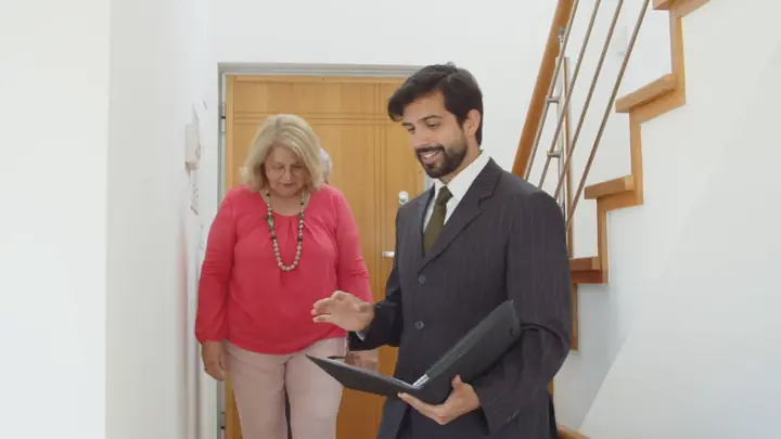 An agent talking with an older couple in a hallway of a home