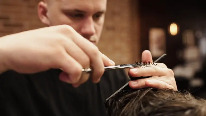 A barber cutting a man's hair with scissors