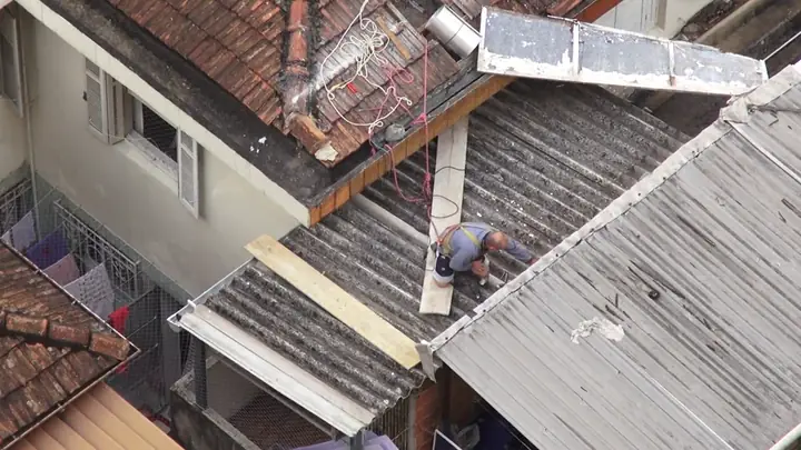 A roofer on a pitched residential roof, seen from above